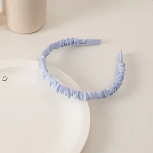 Detail of light blue scrunchie headband with pleated satin fabric texture and soft sheen