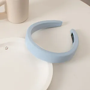 Close-up of light blue padded sponge headband with handmade label on inner side