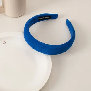 Detail of blue velvet sponge headband with HAND MADE label on white ceramic plate