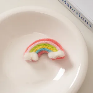 Detailansicht der handgemachten Regenbogen-Haarspange aus Wollfilz mit weißen Wolken