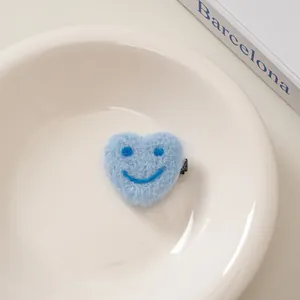 Detail einer hellblauen herzförmigen Wollfilz-Haarspange mit blauem Smiley-Stickerei