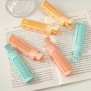 Set of 6 colorful hair root volume clips in pastel pink, yellow and green on a book