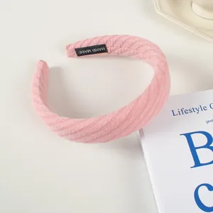 Détail du serre-tête éponge tricoté rose avec étiquette faite main et texture côtelée
