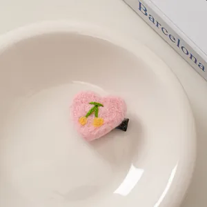 Detail von rosa herzförmiger Wollfilz-Haarspange mit süßer Kirschstickerei-Verzierung
