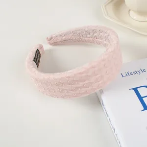 Détail d'un serre-tête rembourré rose clair avec tissu à bulles sur fond blanc
