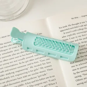 Mint green hair root clip with comb teeth on a book for natural hair volume