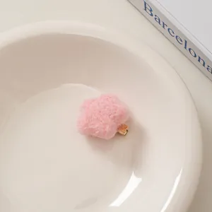 Nahaufnahme der rosa flauschigen Stern-Haarklammer auf einer Keramikschale