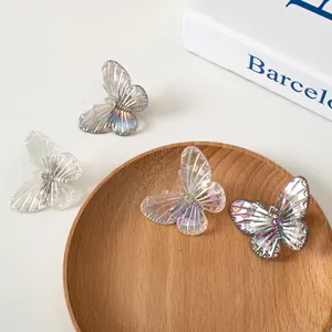 Dettaglio di quattro fermagli a farfalla con finitura perlata iridescente su vassoio di legno