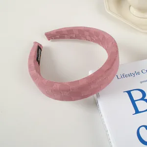 Détail du serre-tête en éponge rose avec texture damier et étiquette faite main