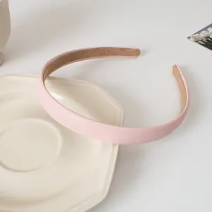 Détail d'un serre-tête en similicuir rose avec doublure antidérapante en daim marron