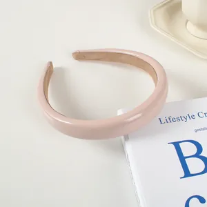 Détail d'un serre-tête en cuir rose brillant rembourré avec doublure en velours marron