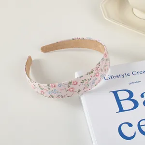 Détail d'un serre-tête en tissu rose à fleurs avec doublure antidérapante sur fond