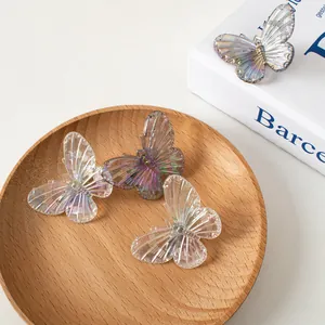 Dettaglio di fermagli per capelli a farfalla laser iridati su display in legno e libro