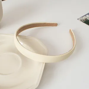 Gros plan d'un serre-tête en cuir crème avec doublure antidérapante sur plateau céramique