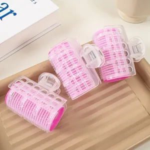 Detail von drei rosa Lockenwicklern mit transparenten Clips auf einem dezenten Tablett