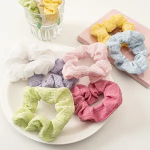 Macro detail of assorted pastel seersucker scrunchies showing soft waffle textures