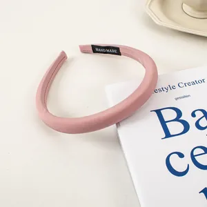 Gros plan d'un serre-tête en satin rose rembourré avec étiquette fait main