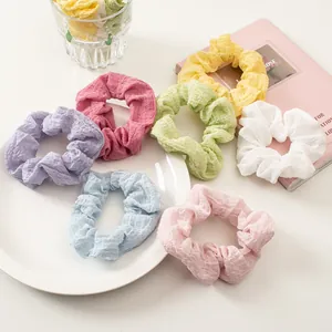 Macro detail of multi-color seersucker scrunchies with soft waffle texture and pastel tones