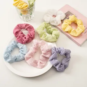 Macro view of seersucker scrunchies in various pastel colors on a white surface