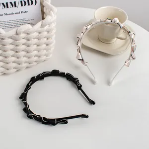 Detail of elegant black and beige bow headbands with fabric texture on a white table