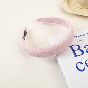 Gros plan du serre-tête en éponge alvéolée rose avec étiquette faite main sur livre