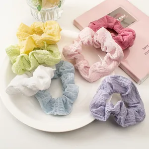 Close-up of colorful seersucker scrunchies in pastel tones on a white ceramic plate