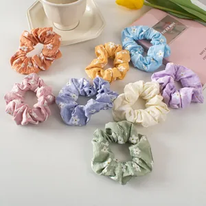 Set of floral scrunchies in pastel colors with daisy prints on soft fabric texture