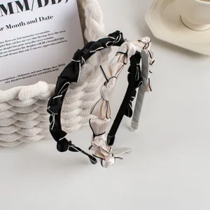 Detail of satin bow headbands with contrast piping and pleated design in elegant black and pink