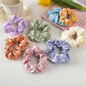 Flat lay macro of seven colorful floral cotton scrunchies with daisy prints and tulip decor