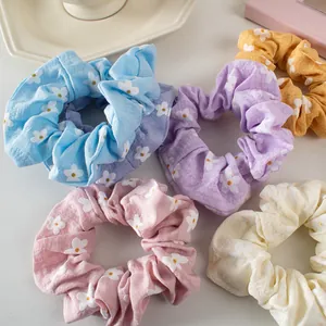 Five-piece set of floral scrunchies in pastel colors with small daisy patterns on fabric