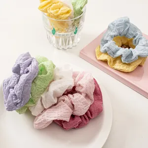Detailed view of colorful seersucker hair scrunchies with wavy pleated texture in a ceramic bowl