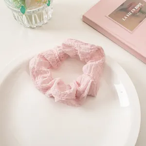 Detail of light pink crinkle seersucker scrunchie on a decorative white ceramic plate