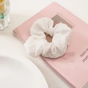 Close-up of white seersucker scrunchie with wrinkled texture on a pink notebook