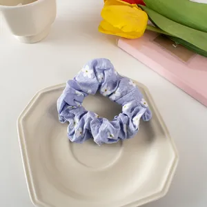 Close-up of lavender floral scrunchie with white daisy patterns on a ceramic plate