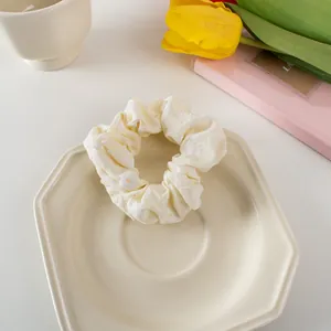 Close-up of a cream floral scrunchie on a ceramic plate with tulip and notepad decorations