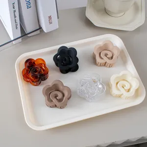 Vue à plat de six pinces à cheveux florales aux couleurs mates sur un plateau blanc