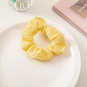 Detail of light yellow seersucker scrunchie with waffle texture on a white plate