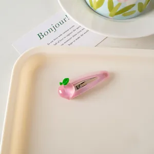 Detalle de la pinza para el pelo con melocotón rosa translúcido en bandeja crema