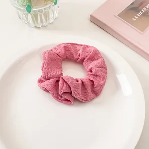 Detail of pink seersucker scrunchie with bubble texture on a white ceramic plate