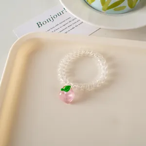 Detalle de un coletero en espiral transparente con un lindo colgante de melocotón rosado