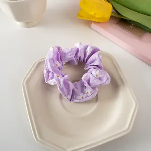 Detail of light purple floral scrunchie with daisy print on a decorative white plate