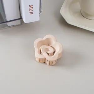 Gros plan sur une pince à cheveux fleurie mate crème sur un bureau au style épuré
