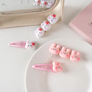 Gros plan de barrettes lapin rose avec détails fraises sur un plateau décoratif
