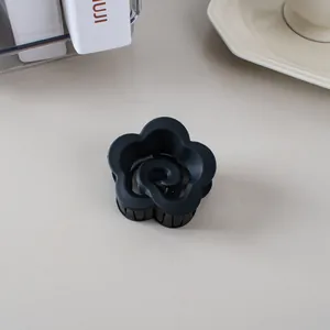 Gros plan sur la pince à cheveux fleur noire mate avec centre en spirale