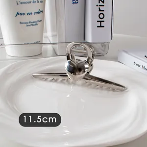 Détail d'une pince à cheveux argentée de 11,5cm avec décor cœur sur un plateau céramique