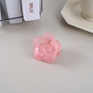Vue détaillée d'une pince à cheveux fleur rose mat sur un bureau minimaliste
