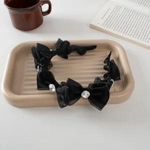 Close-up of black mesh bow headband with crystal on a ceramic tray in a cozy scene
