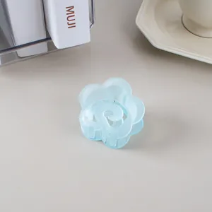 Détail d'une pince à cheveux fleur bleu clair mat avec un motif de pétales de rose