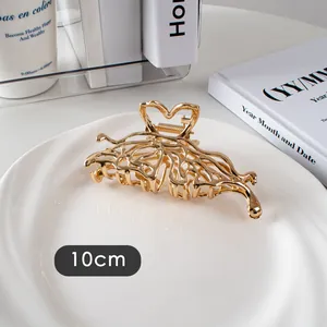 Détail d'une pince à cheveux de 10cm en métal doré avec motif de cœur sur un plateau