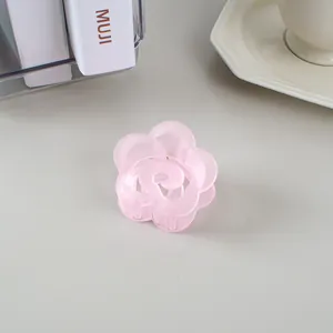 Vue macro d'une pince à cheveux fleur rose mat sur un fond de bureau minimaliste